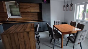 Eine moderne Küche mit Holzschränken, einem Esstisch mit sechs Stühlen und einem Fenster mit Außenblick.