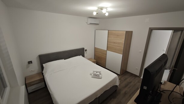 Ein Schlafzimmer mit einem Bett, einem Nachttisch, einem Kleiderschrank und einem Fernseher.
