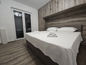 A bedroom with a bed, a wooden headboard, a sliding glass door, and a white wall. - Beautiful Villa Pauliana (Povljana)