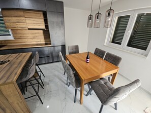 A modern dining area with a wooden table and grey upholstered chairs. - Beautiful Villa Pauliana (Povljana)
