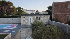 Ein Poolhaus aus Stein mit Tür und Fenstern, umgeben von einer Steinmauer und einem Schwimmbecken mit farbenfrohem Design.