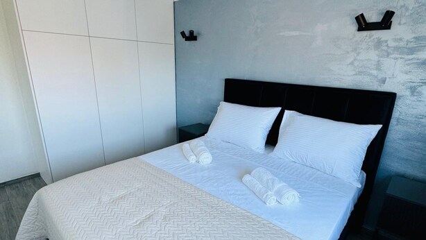A modern hotel room with a large bed, a wardrobe, and a unique ceiling light fixture. - Stylish Couple Getaway Near Beach (Sukosan)