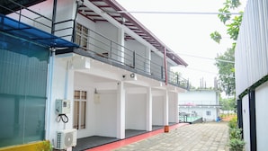 A building with a covered outdoor area, air conditioning units, and a red pathway. - Amila Resort (Habarana)