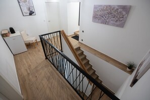 A staircase with wooden steps and a black railing, leading to a landing with a white door and a small desk with a plant. - Holiday Home Lantina With Pool (Novigrad)