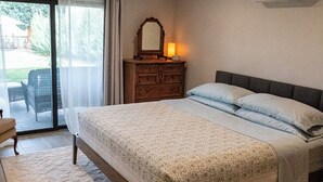 Un dormitorio con una cama grande, un aparador, un espejo y un equipo de aire acondicionado.