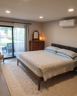 Quarto com uma cama grande, cômoda, espelho e ar condicionado.