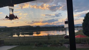 Vista de un lago al atardecer, con una escultura de pájaro colgante y un paraguas rojo.