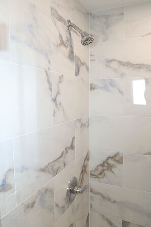 Un bagno con piastrelle in marmo e una doccetta.