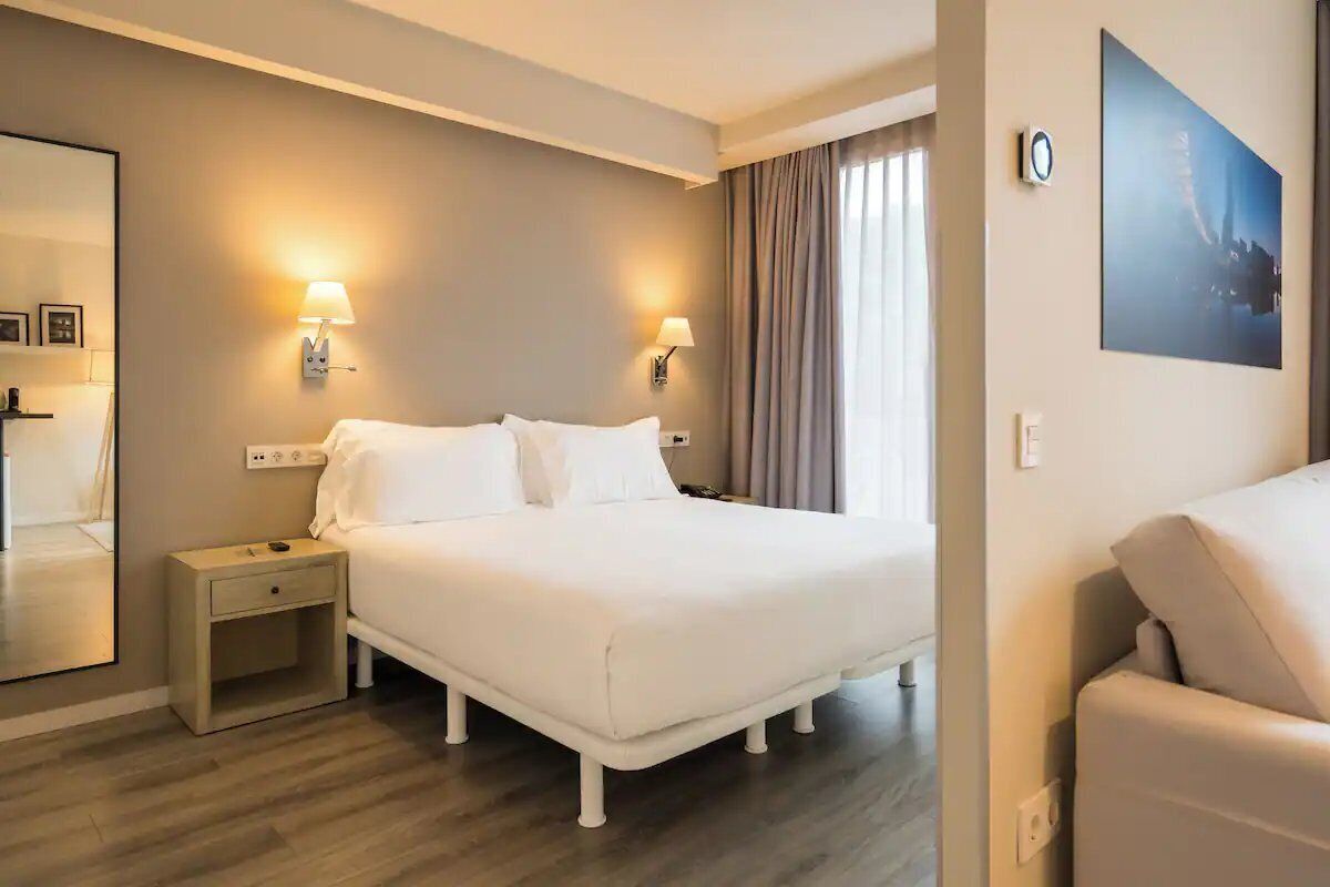 Relax in a calm, airy room with warm bedside lighting.