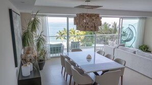 Ein moderner Essbereich mit einem großen Tisch, Stühlen und Blick auf das Meer.