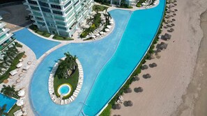 An aerial view of a resort with a central swimming pool, a beach area, and a multi-story building with balconies. - Ocean View, PtoVallarta Peninsula/3SZ• (Puerto Vallarta)