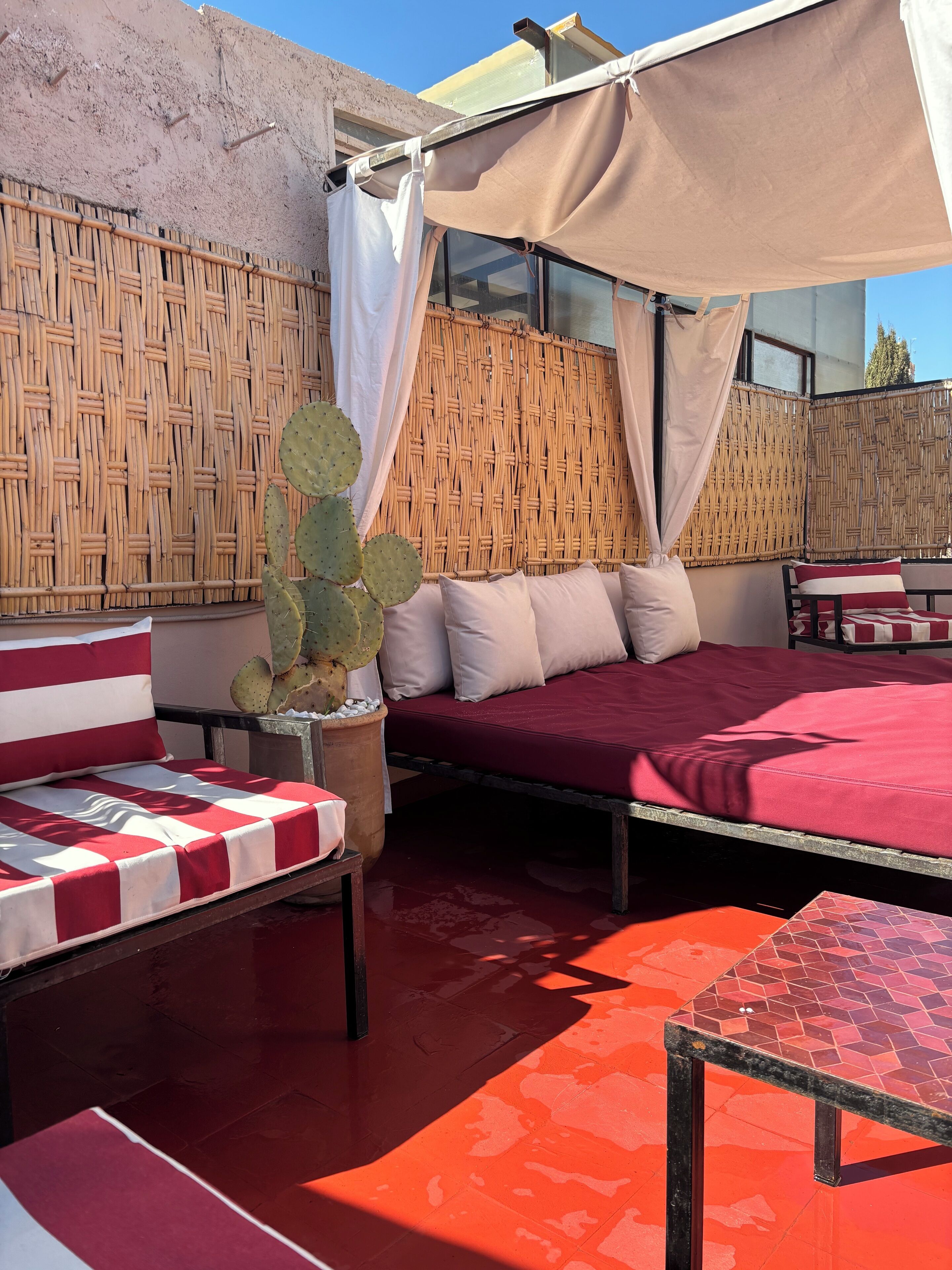 A cozy outdoor seating area with a cushioned bench, a table, and a wicker partition.