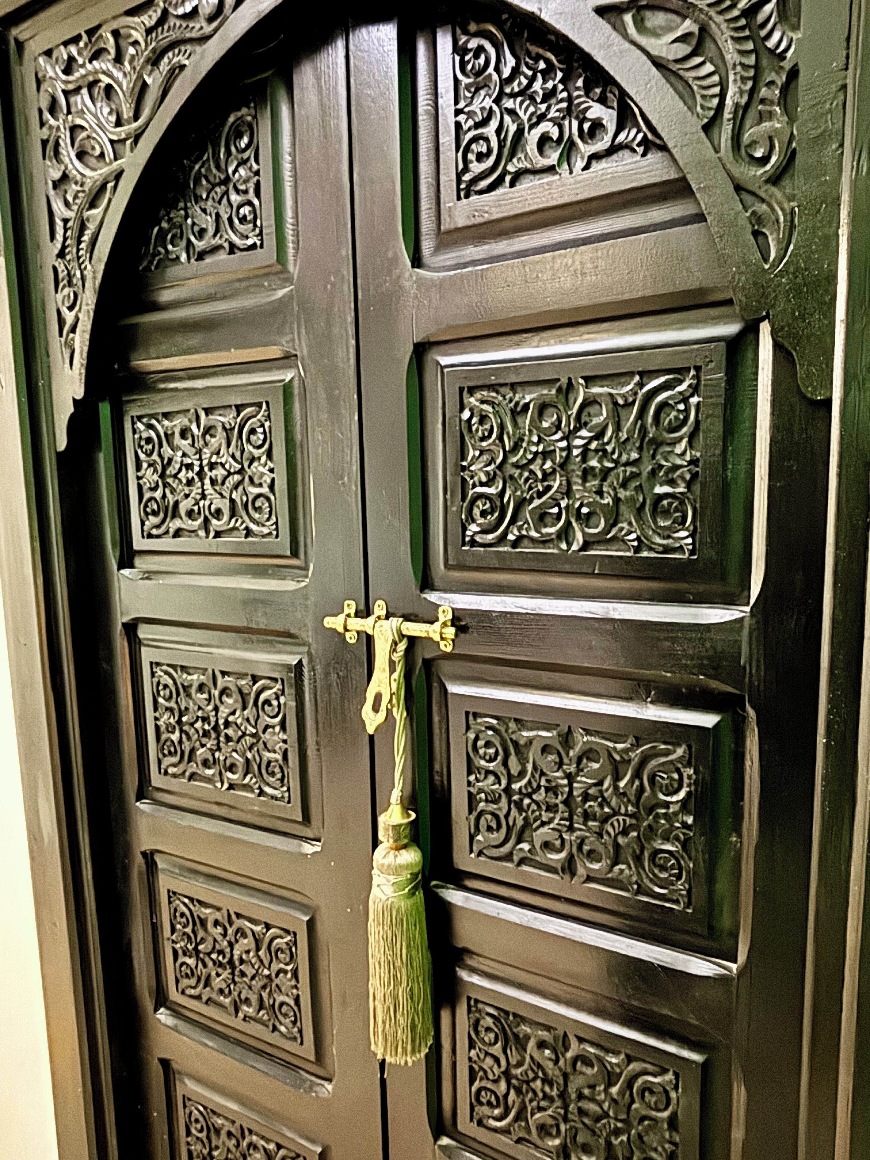 A dark wooden door with intricate carvings and a brass door handle.