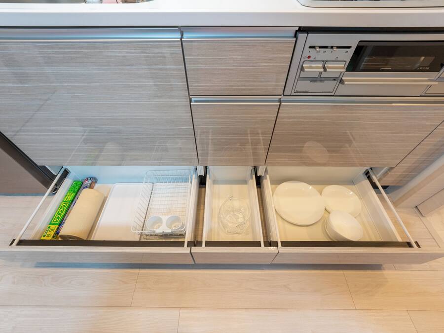 Uma gaveta de cozinha com utensílios, pratos e um rolo de papel toalha.