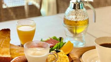 Una colazione con pane tostato, uova strapazzate, salsiccia, un bicchiere di succo d'arancia, un bicchiere di latte, una tazza di caffè e una bottiglia di miele.