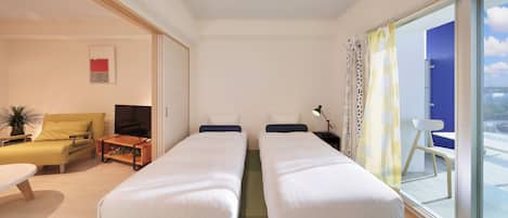 A hotel room with two beds, a sofa, a small table, a TV, and a view of the outdoors.