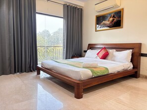 A neatly made bed with white linens and a green and beige throw, a wooden headboard, and a painting above it. - Fortune Home Service Apartment 3BHK, J-130 Saket (New Delhi)