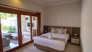 A modern bedroom with a large bed, a sliding glass door to a balcony, and a flat-screen TV on a stand. - Juada Garden (Seminyak)