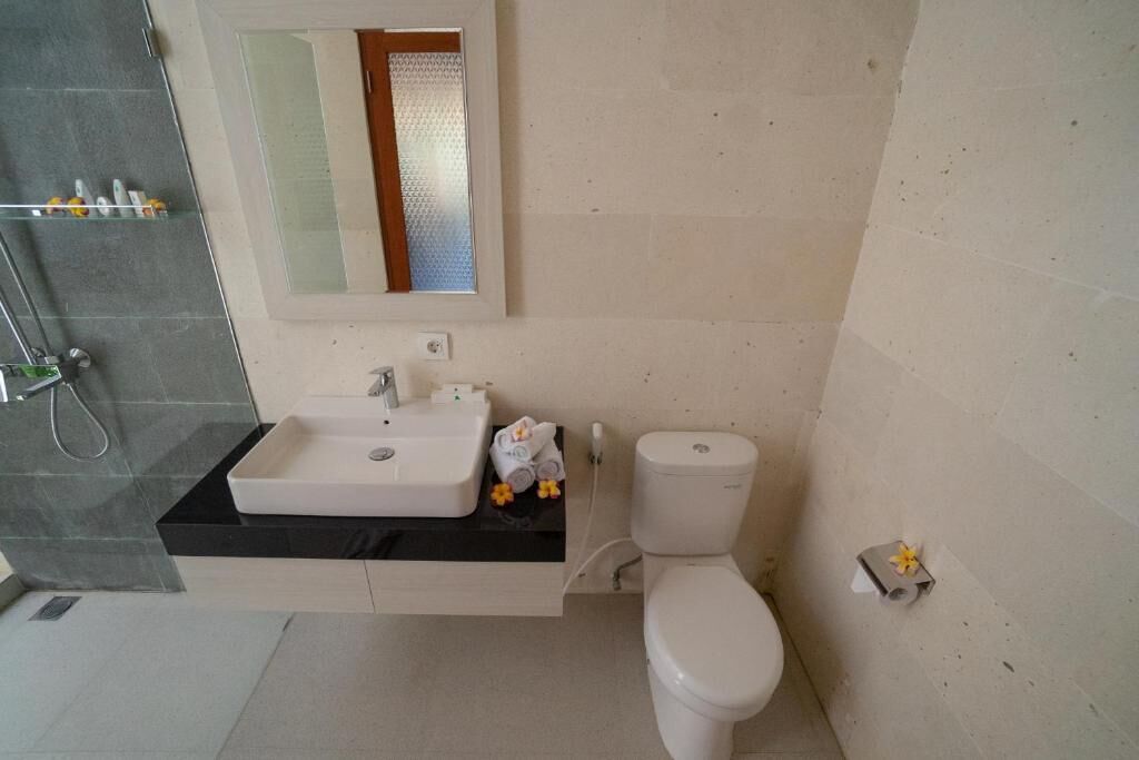 Une salle de bain avec un lavabo blanc, un miroir et des toilettes.