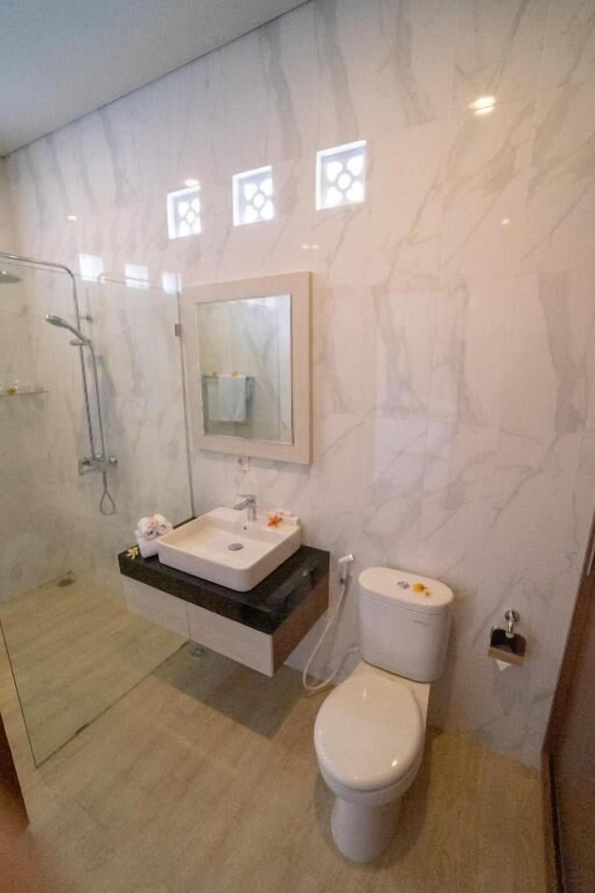 Un baño con lavamanos, inodoro y ducha blancos.