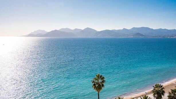 A coastal view with a clear sky, calm sea, and distant mountains. - Magnifique 3 Pieces Vue Mer Cannes (Cannes)