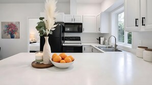 Een moderne keuken met witte kasten, een zwarte koelkast, een magnetron en een spoelbak.