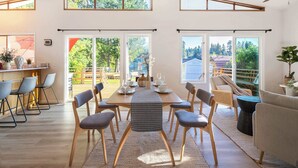 Een ruime eetruimte met een lange tafel, meerdere stoelen en een plafondventilator.