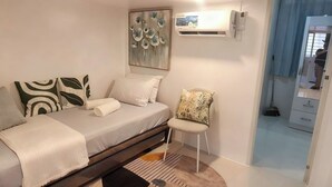 Ein modernes Schlafzimmer mit einem Bett, einem Sessel, einem Bild und einer Klimaanlage.