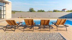 A modern outdoor pool area with four wooden lounge chairs and a clear view of the surrounding landscape. - Beautiful Villa for 6 Near Zadar Beach (Zadar)