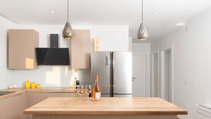 A modern kitchen with a central island, stainless steel appliances, pendant lighting, and a flat-screen TV mounted on the wall. - Beautiful Villa for 6 Near Zadar Beach (Zadar)