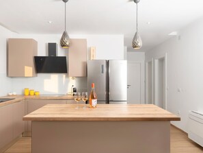 A modern kitchen with a central island, stainless steel appliances, pendant lighting, and a flat-screen TV mounted on the wall. - Beautiful Villa for 6 Near Zadar Beach (Zadar)