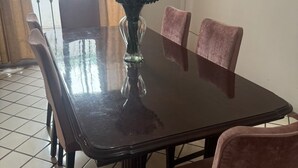 Une table à manger ornée d’un vase de fleurs, entourée de chaises.