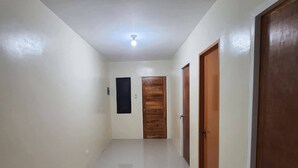 A hallway with white walls and a shiny floor, leading to a wooden door at the end. - NEWLY RENOVATED ROOMS NOW OPEN FOR INQUIRIES AND RESERVATIONS (Angeles Pampanga)