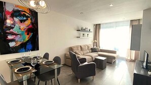 Un soggiorno moderno con un divano componibile, un tavolo da pranzo per quattro persone e un grande quadro astratto appeso al muro.