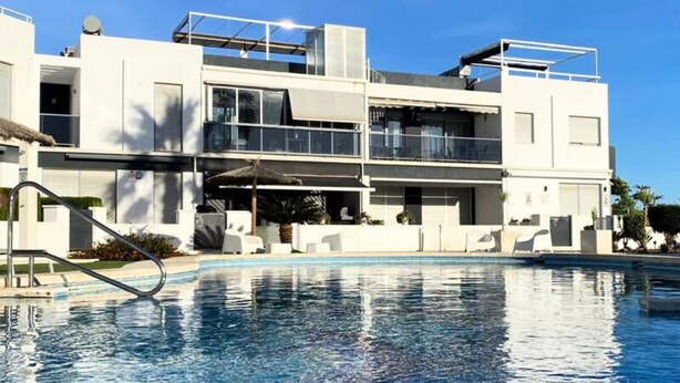 Un edificio moderno a due piani con una piscina di fronte.