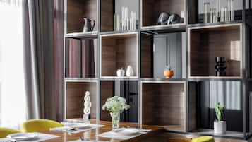 A modern dining area with a wooden table, yellow chairs, and a built-in bookshelf with various decorative items.