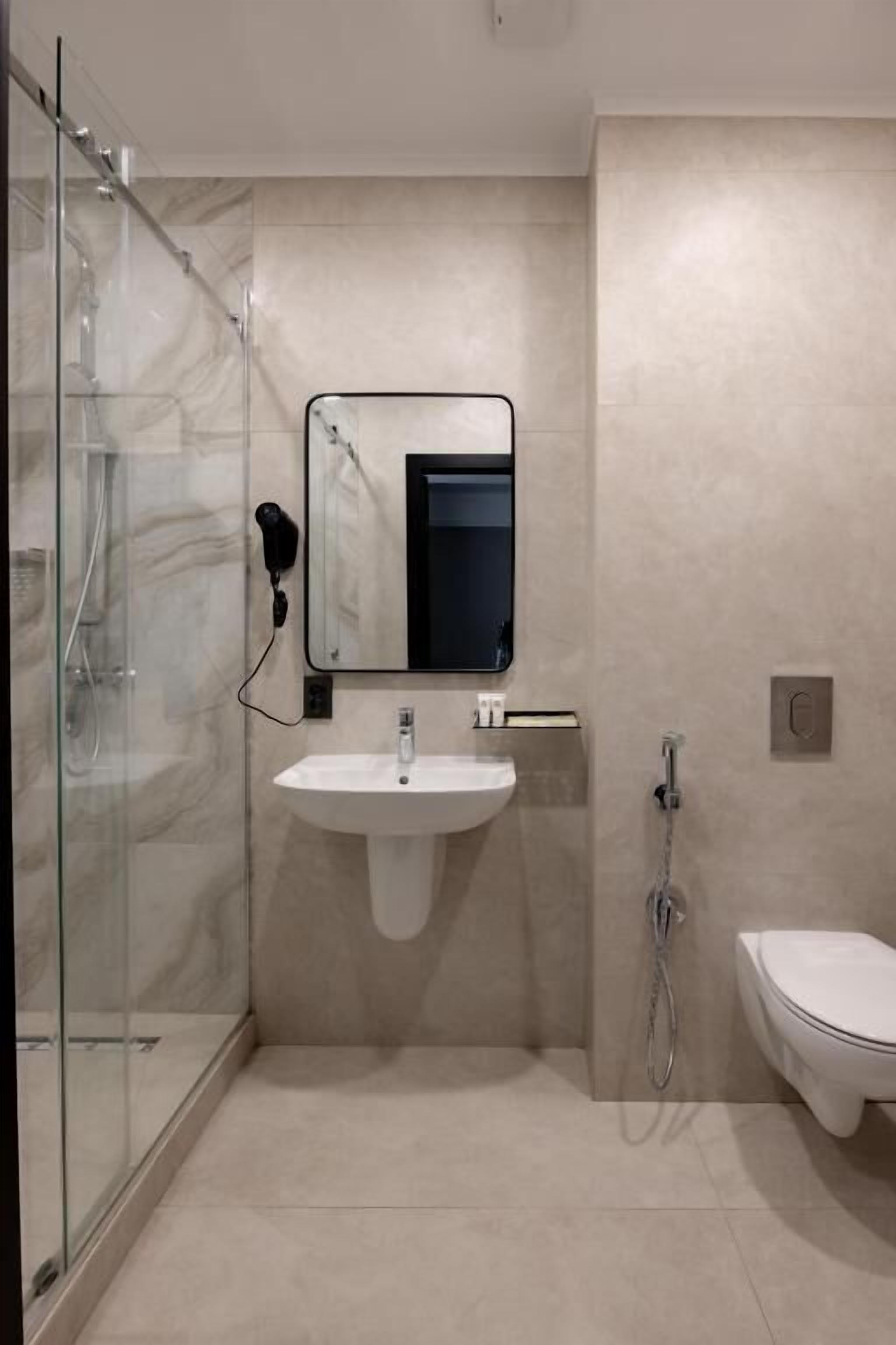 Un baño moderno con cabina de ducha de vidrio, un lavabo blanco y un inodoro.