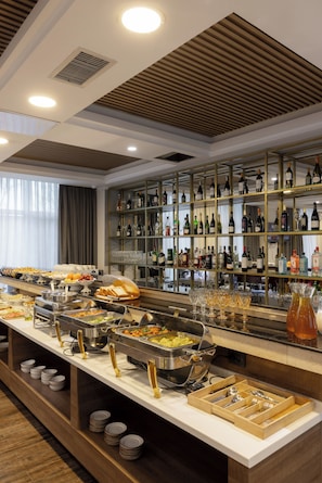 A buffet area with various food stations, a wine and liquor display, and a seating area with a view of the outdoors. - Mountain View Residence Almaty (Almaty)