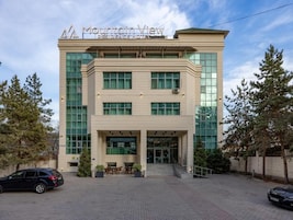 Un moderno edificio de hotel con una entrada destacada, ventanas amplias y un área de estacionamiento.