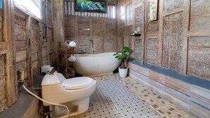 Une salle de bain rustique avec une baignoire sur pieds, des toilettes et une plante en pot.