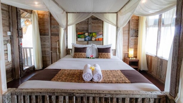 A large bed with a canopy, a wooden headboard, and a bedside table with a lamp.