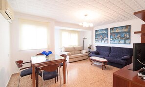 Ein Wohnzimmer mit Esstisch, Stühlen, einer Couch und Kunstwerken an der Wand.