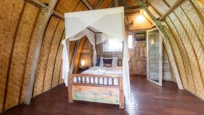 A rustic wooden room with a four-poster bed, wooden walls, and a sloped ceiling. - Two Bedroom Bungalow (Ubud)