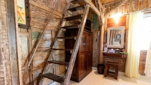A rustic room with a wooden staircase, a wooden cabinet, and a small stool. - Two Bedroom Bungalow (Ubud)