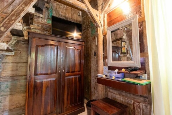 A rustic wooden interior with a wooden wardrobe, a small bench, and a mirror on the wall. - Two Bedroom Bungalow (Ubud)