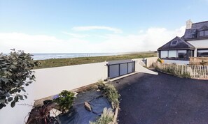 Une propriété située sur la côte, dotée d’une allée pavée, d’une entrée sécurisée par un portail et offrant une vue sur la mer.