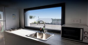 Une cuisine moderne équipée d’un évier en acier inoxydable, d’une fenêtre, d’un four à micro-ondes et d’une cuisinière à gaz.
