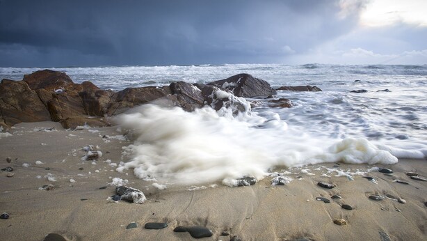Una playa con rocas grandes y olas.