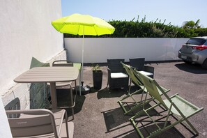 An outdoor seating area with a table, chairs, and a green umbrella. - Ty Mouss' Tiny House with an Ocean View in Plozévet (Plozévet)
