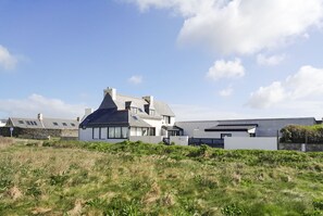 Une maison moderne avec un toit en pente, de grandes fenêtres et une pelouse bien entretenue devant.